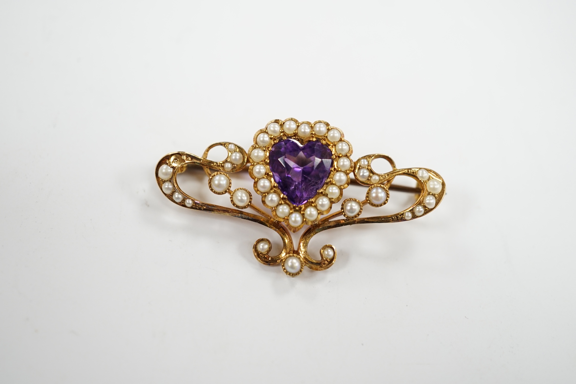 An Edwardian 15ct?, amethyst and seed pearl cluster set bar brooch, with central heart motif, 38mm, gross weight 4.7 grams.